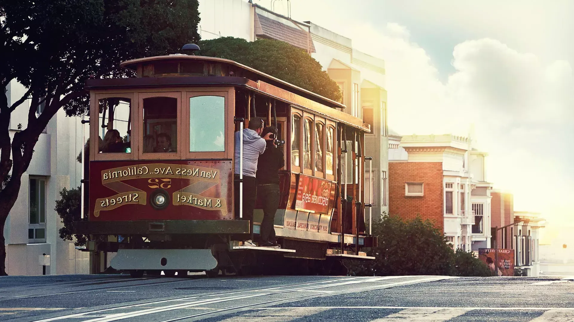 Un téléphérique contourne une colline à San Francisco avec des passagers regardant par la fenêtre.