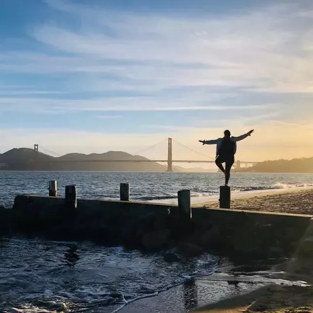 Une femme se tient sur une jetée du quartier Marina de San Francisco, face au Golden Gate Bridge.