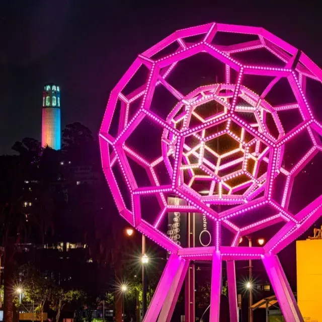 Buckyball brille à l'extérieur de l'Exploratorium, avec la Coit Tower en arrière-plan